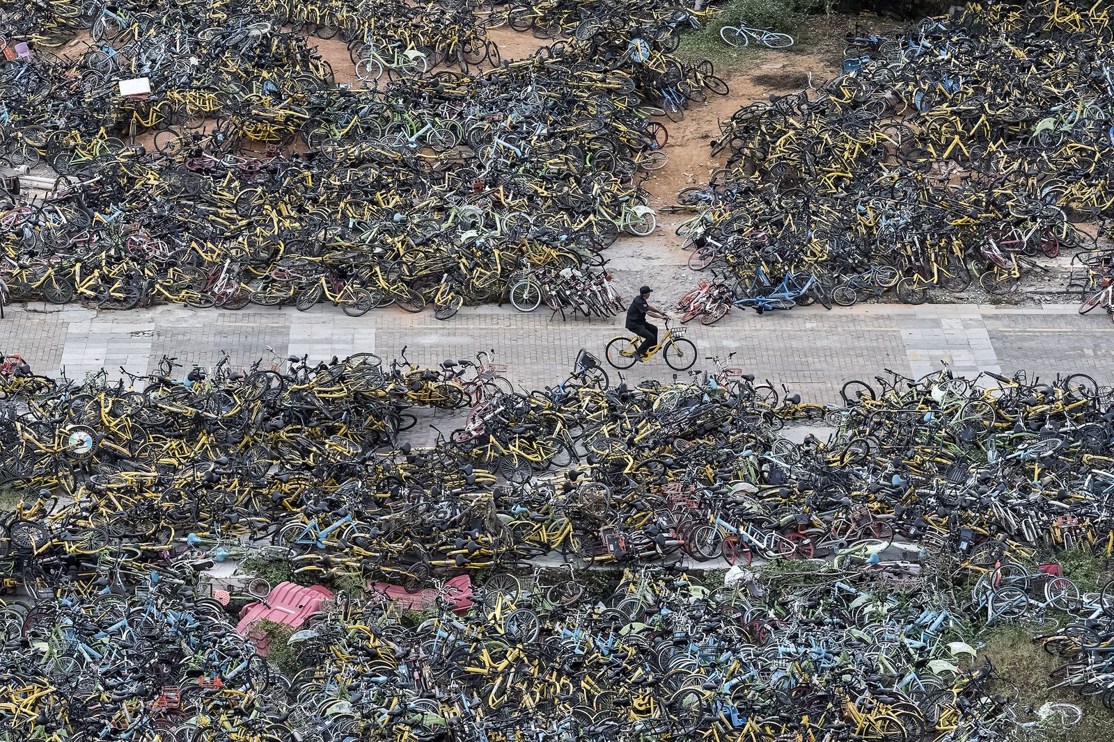 © WU GUOYONG - 16 Shenzhen, China An urban management officer patrols the shared bicycle cemetery on a shared bicycle. 2018/11/07