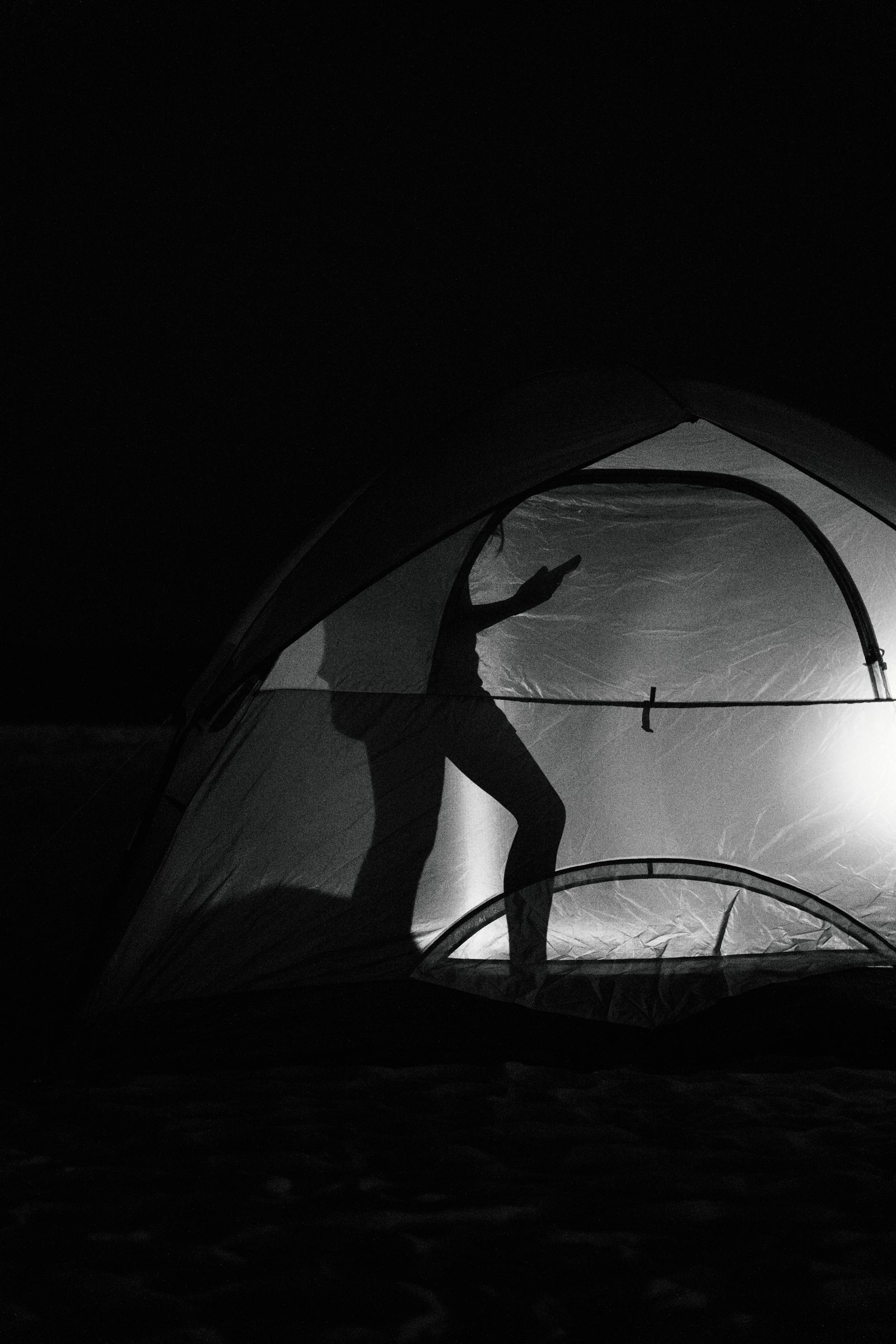 © Paola Chapdelaine - A troop member looks at her phone before sleeping in her tent at the Seaside Heights beach camp.