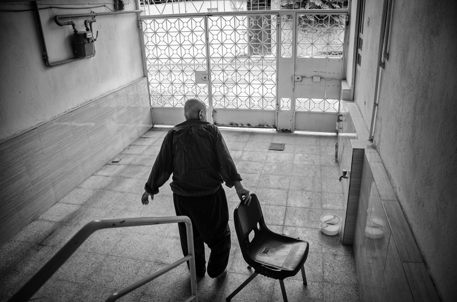 © Khashayar Sharifaee - Grandfather is dragging a chair outside of house so he can sit outside for some time and relax and breathe fresh air.