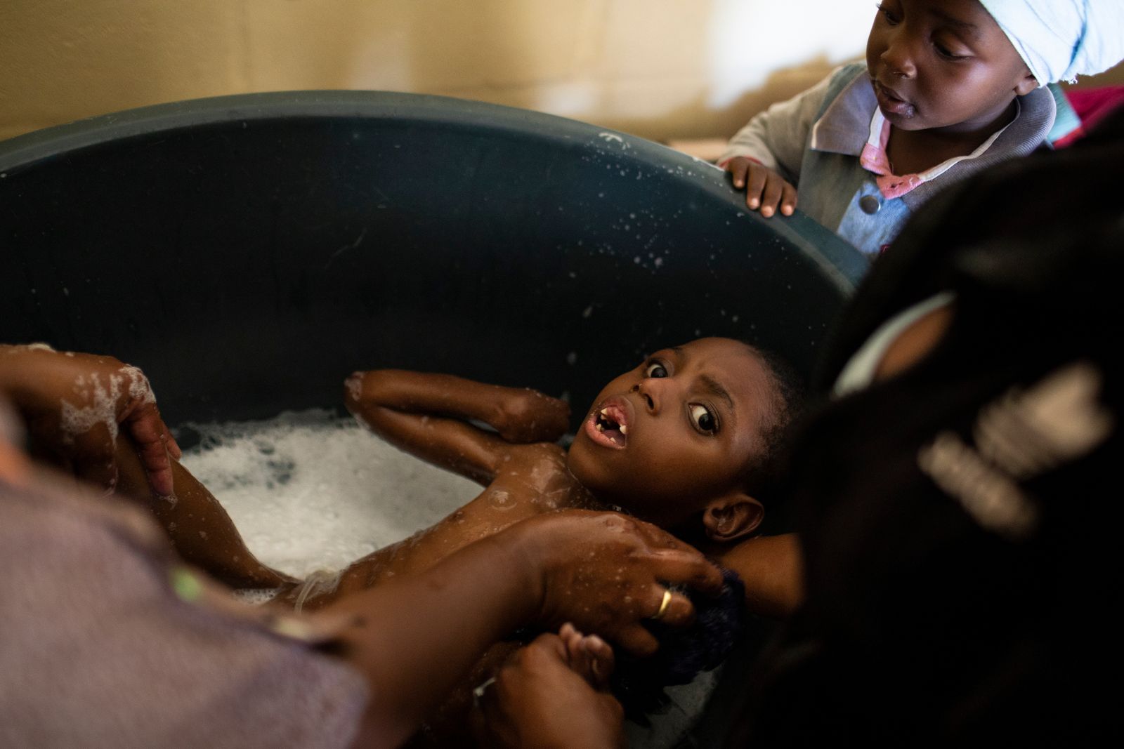 © Ilvy Njiokiktjien - Efewe (6), taking a bath with the help from his mother and grandmother in Samora Machel, a township close to Cape Town.