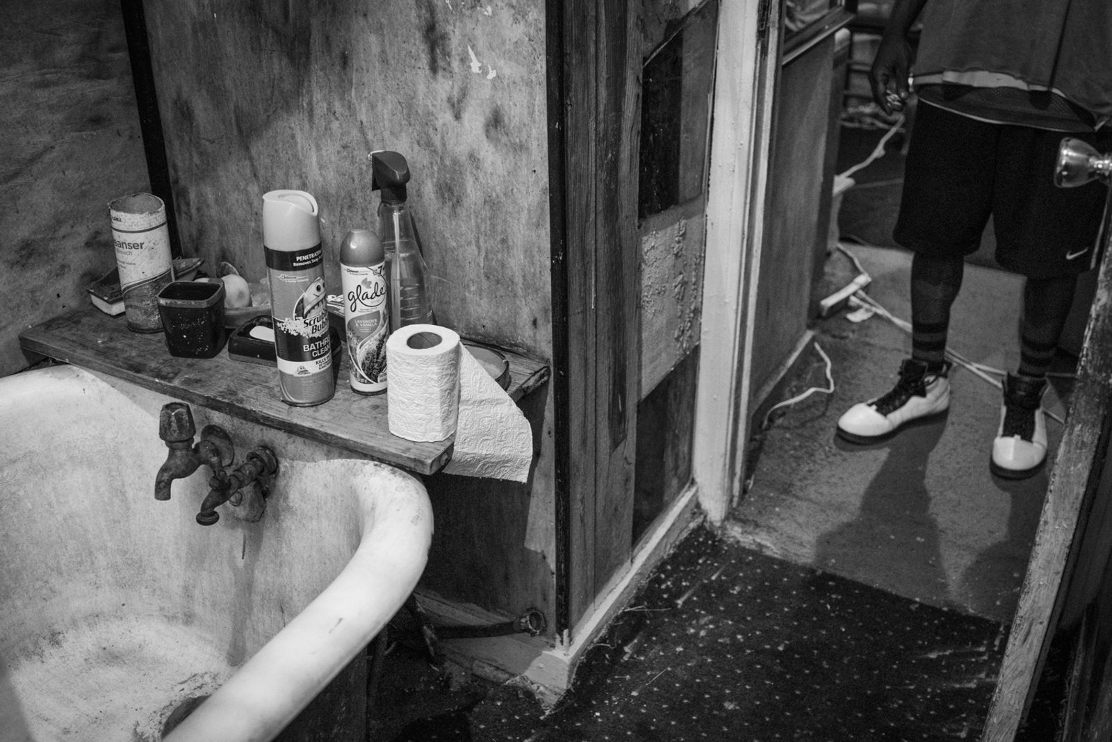 © Richard Sharum - “People” stands in front of his bathroom. Like other residents, he must use toxic groundwater to bathe with. 2018.