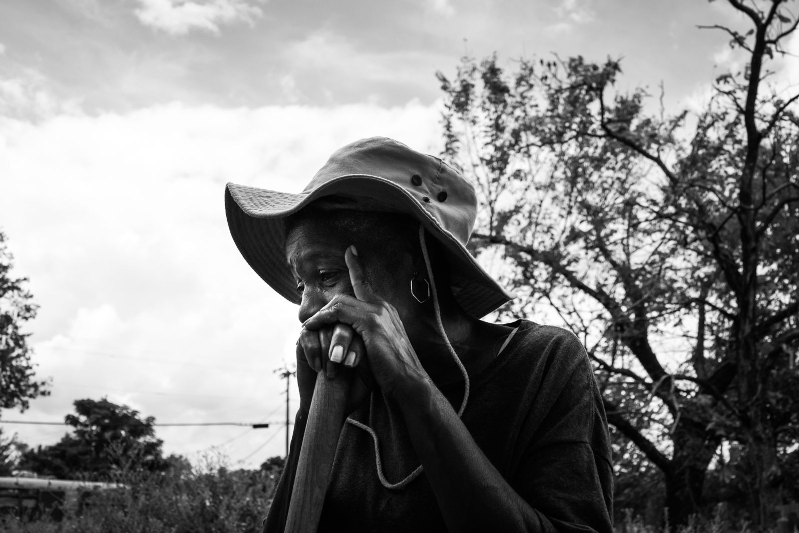© Richard Sharum - Ms. Betty leans on a garden hoe to rest from weeding in her front yard. 2018.
