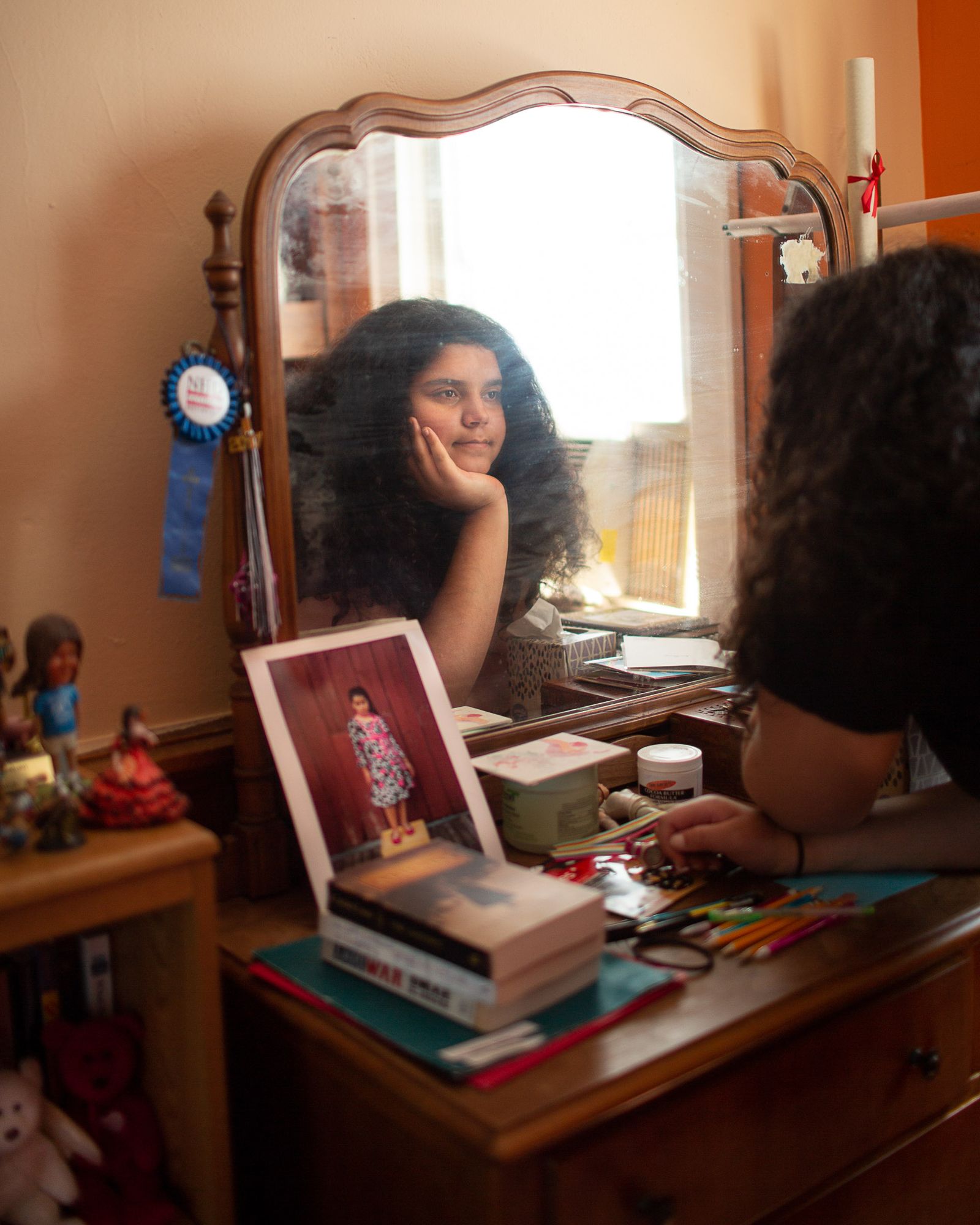 © Lindsay Morris - Tavish gazes in the mirror near a 2010 photo of her younger self at Camp I Am.