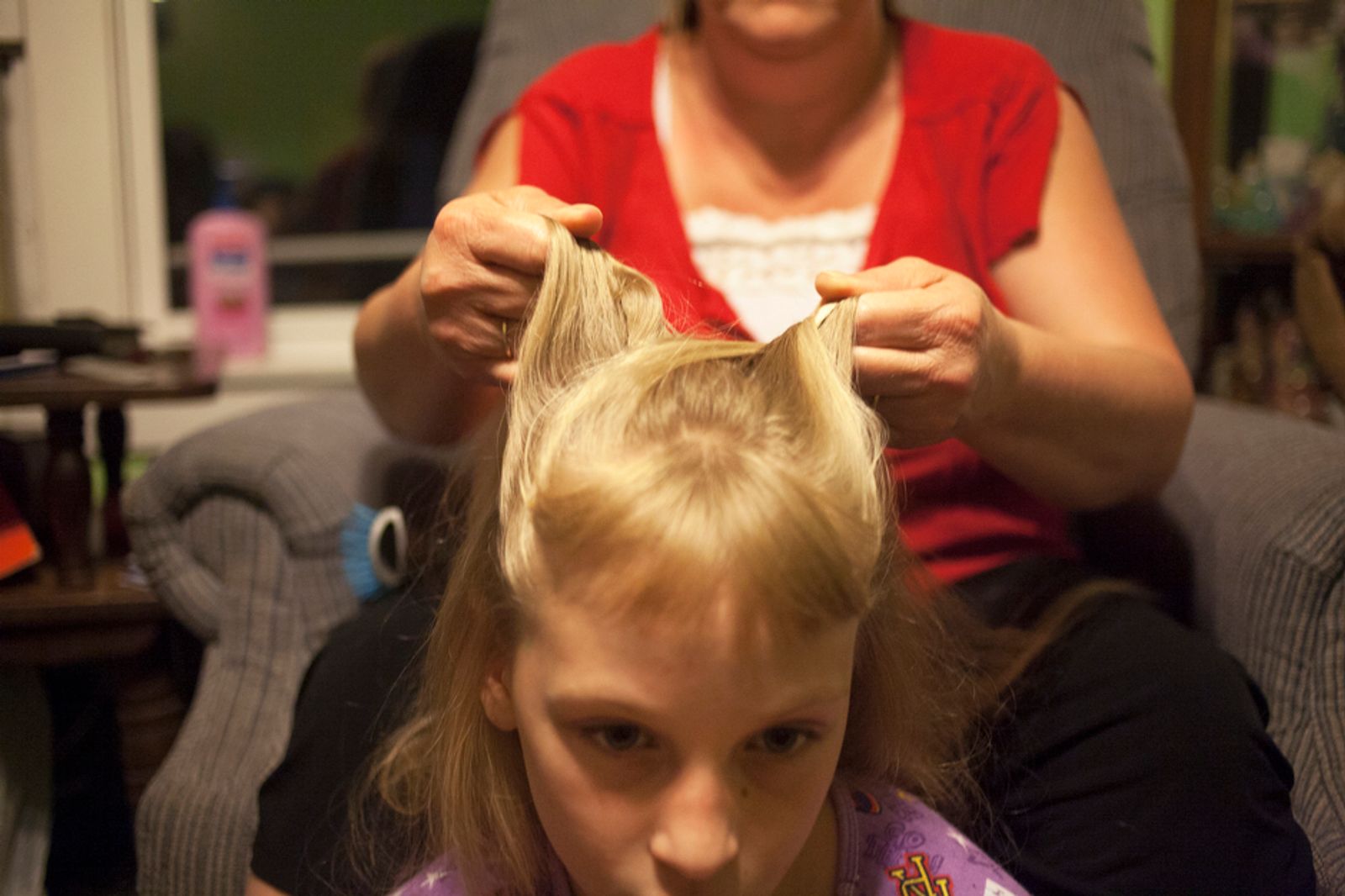 © Maddie Mcgarvey - Lorrie, Sonya's grandmother, braids Sonya's hair before bed. Lorrie is taking care of her daughter Amber's three children.