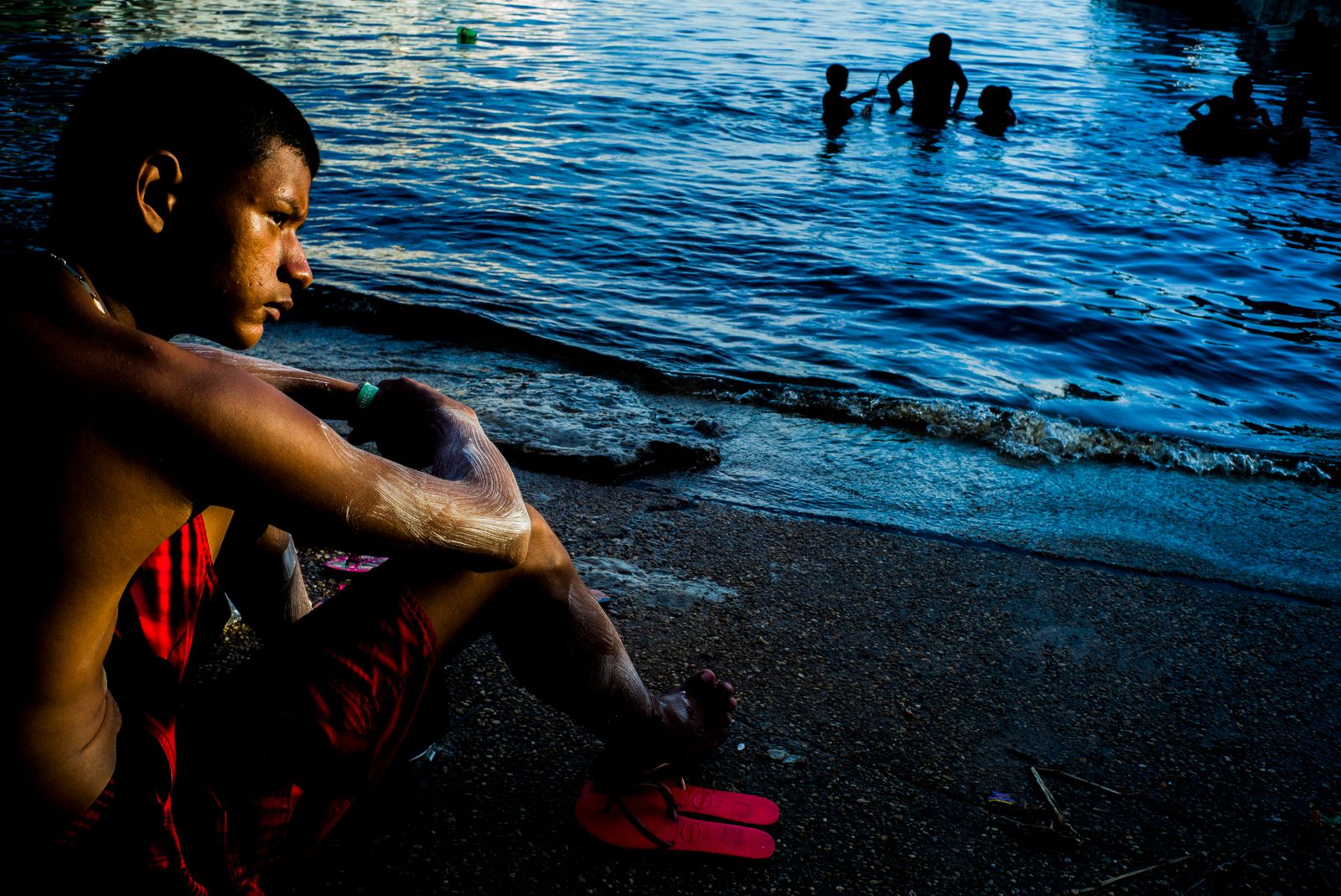 © Raphael Alves - A boy sits next to the Negro River to watch the sunset on May, 27th, 2016, in manaus, Amazonas, Brazil.