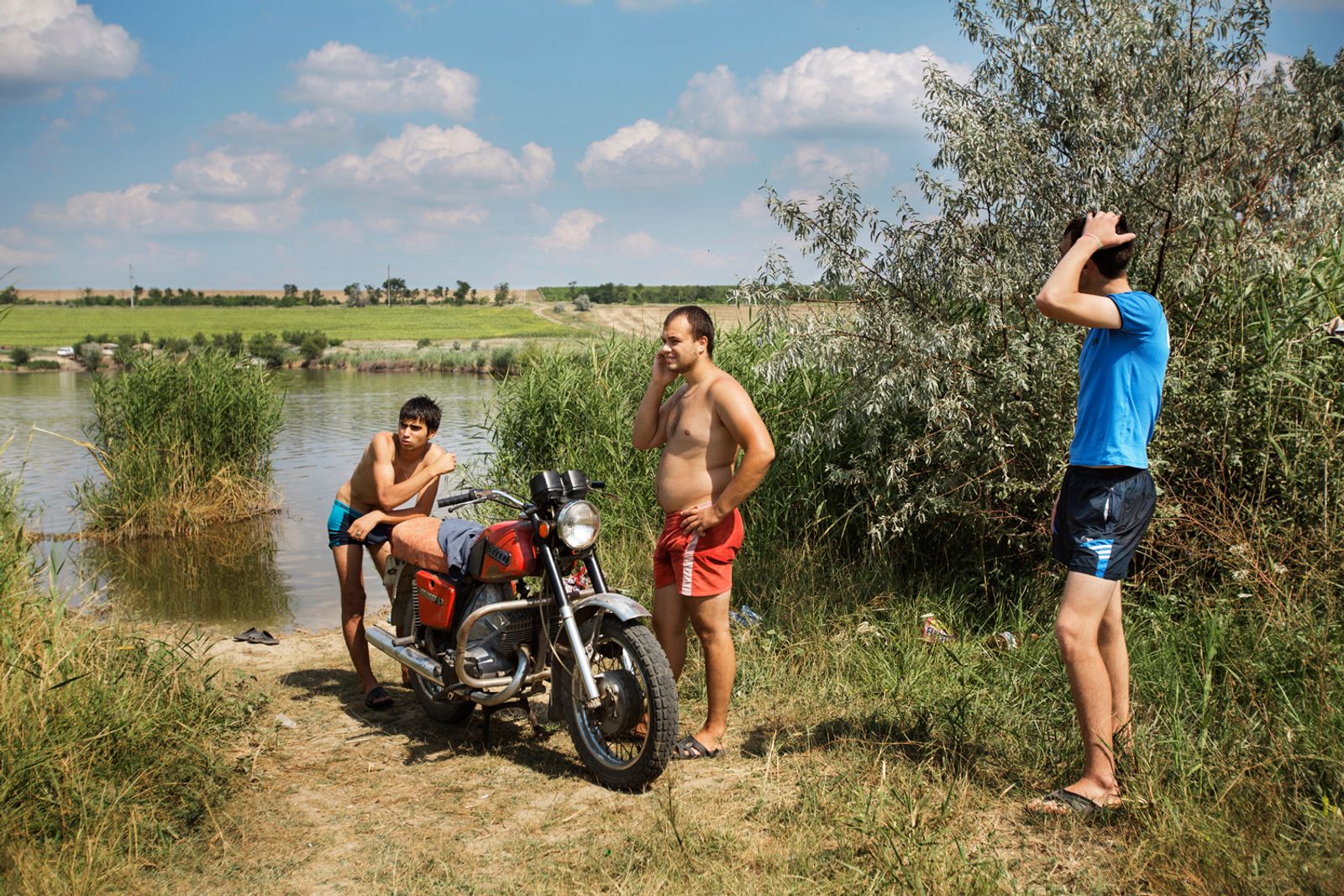 © Alessandro Vincenzi - Moldova. Beshalma, Gagauzia - July 2017Three men after a bath in the lake wait to dry before leaving with their bike.