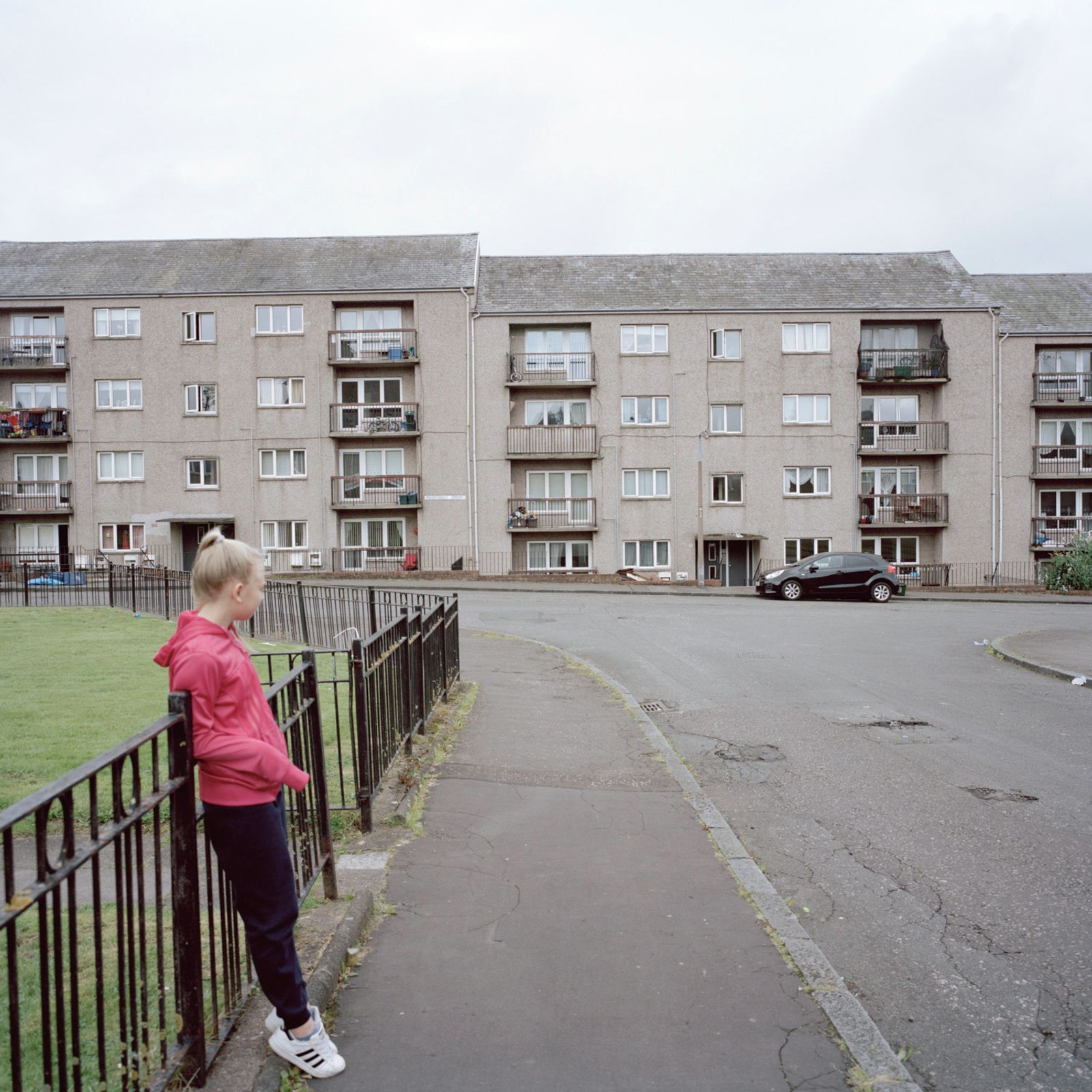 © Margaret Mitchell - Leah in front of her flats. 'Hopefully, I will stay here forever, in this area, this place'