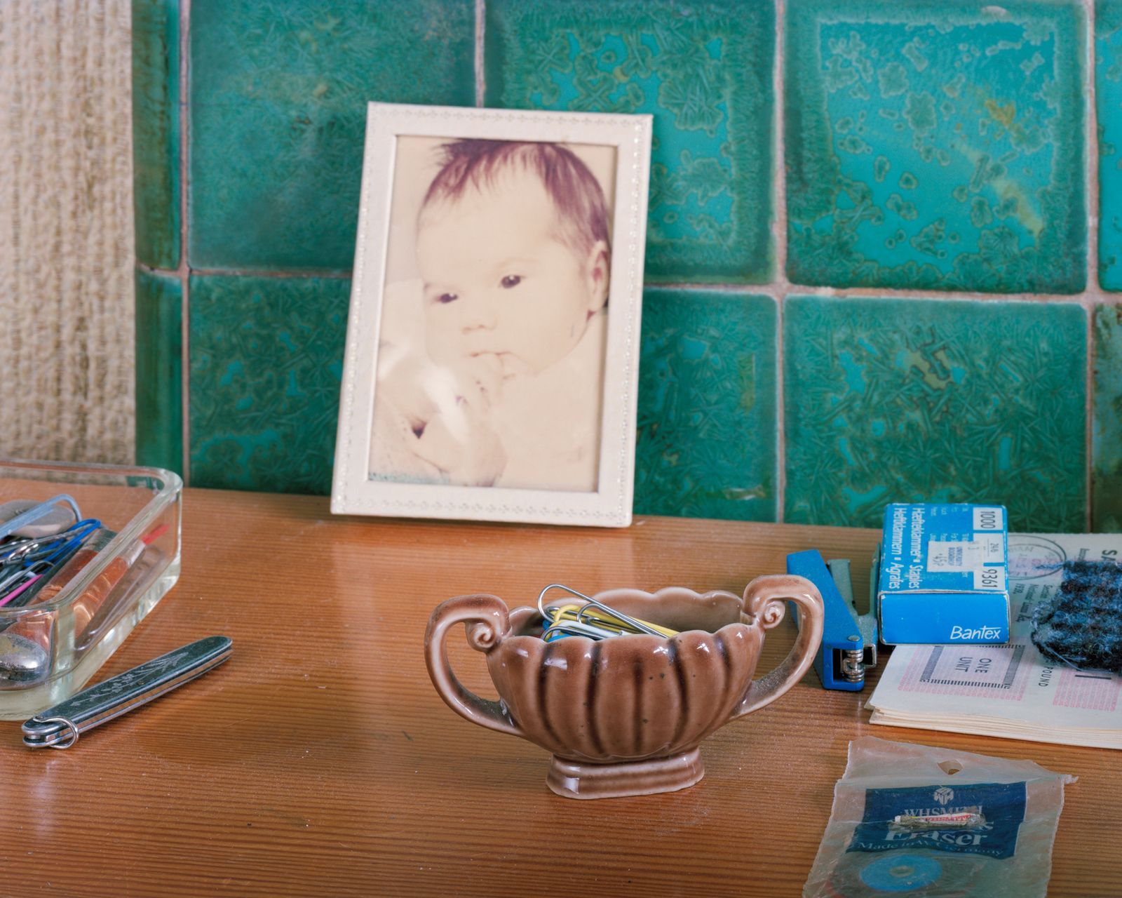 © Oliver Woods - My old desk that dad had been using. In the middle is a framed fading photo of my baby sister Caroline.