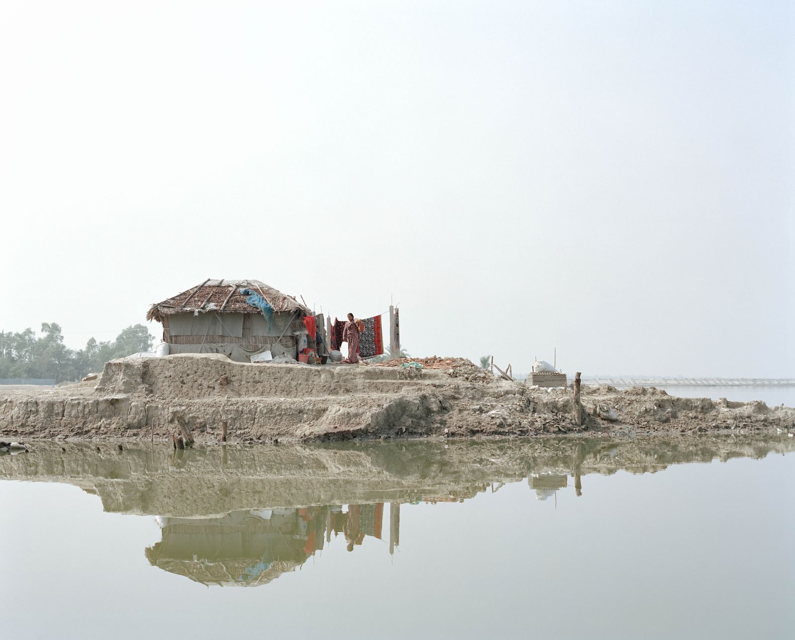© Shunta Kimura - A woman is doing household chores near the house on soil that has gradually decreased due to river erosion.