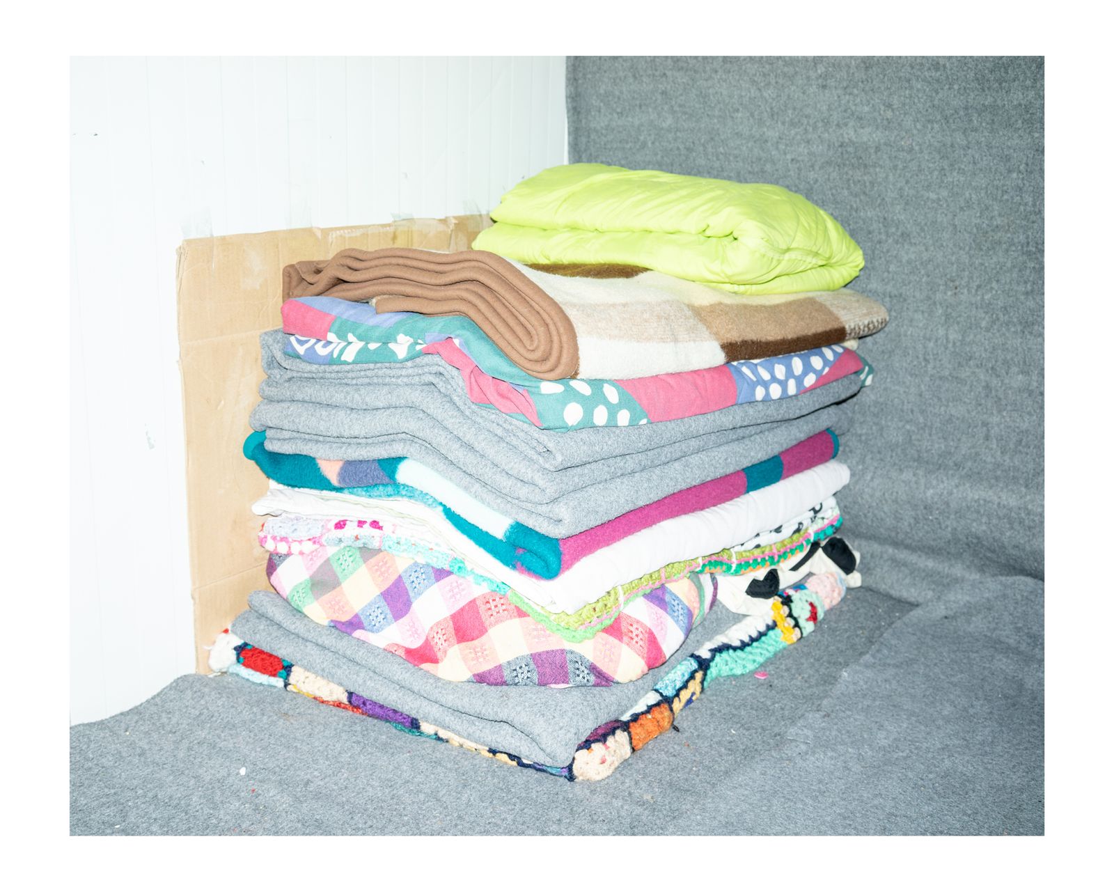© Charlotte Schmitz - Pile of blankets of one family of five persons, who are living on a five square metres area.