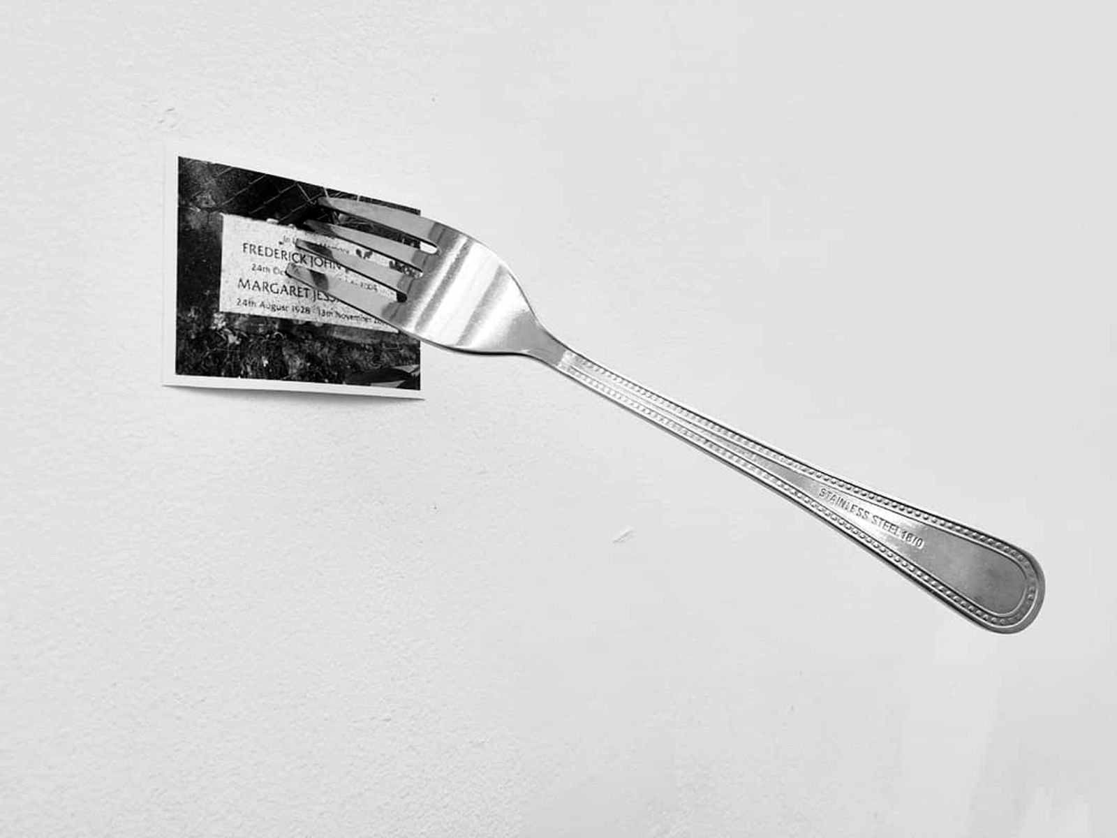 © Jonny Briggs - Consuming (Fork holding a photograph of my Grandparents' grave to the ceiling) 2018