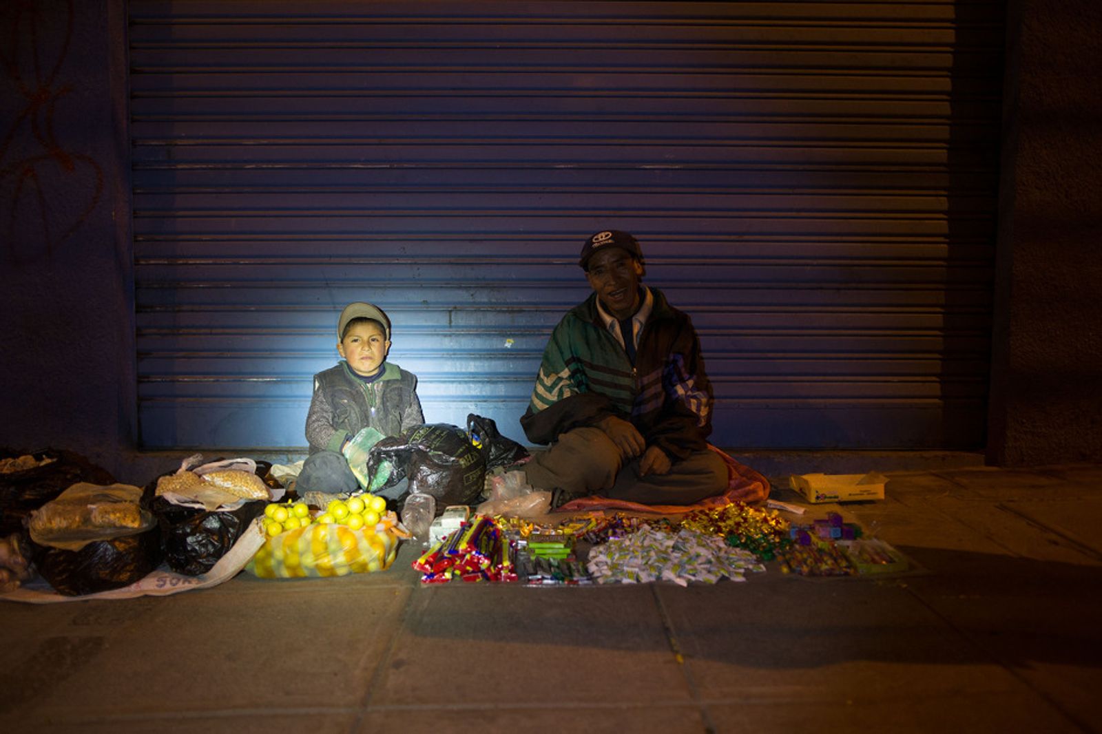 © Toby Binder - A young boy is sitting on a street of La Paz and helping his father to sell lemons, sweets and nuts.