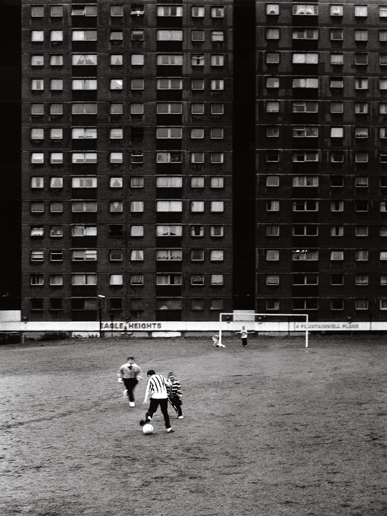 © Toby Binder - Glasgow, Sighthill. Kids playing football in front of a highrise building.