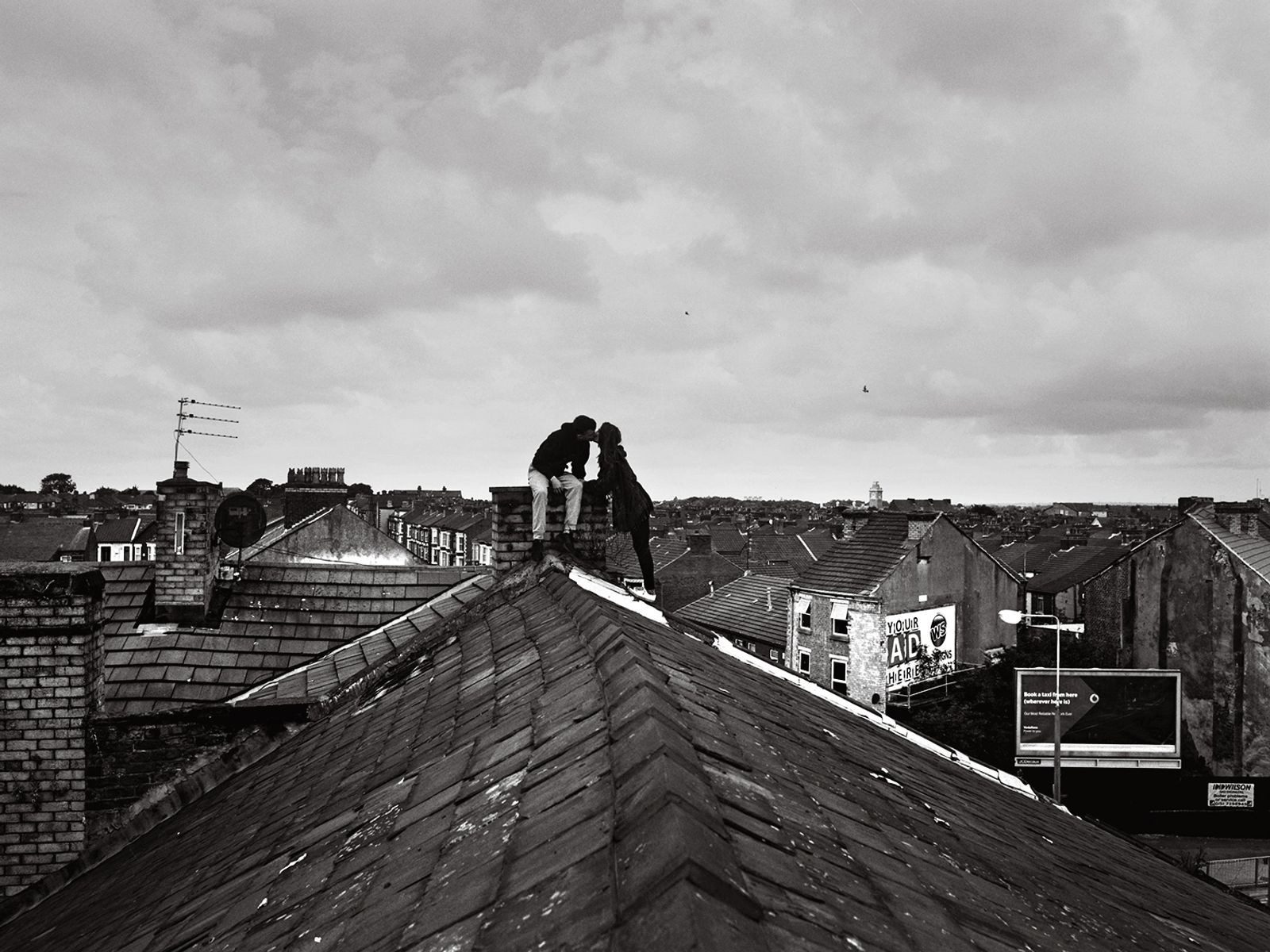 © Toby Binder - Liverpool, Walton. Chloe and Ethan kissing on the rooftop of their house.