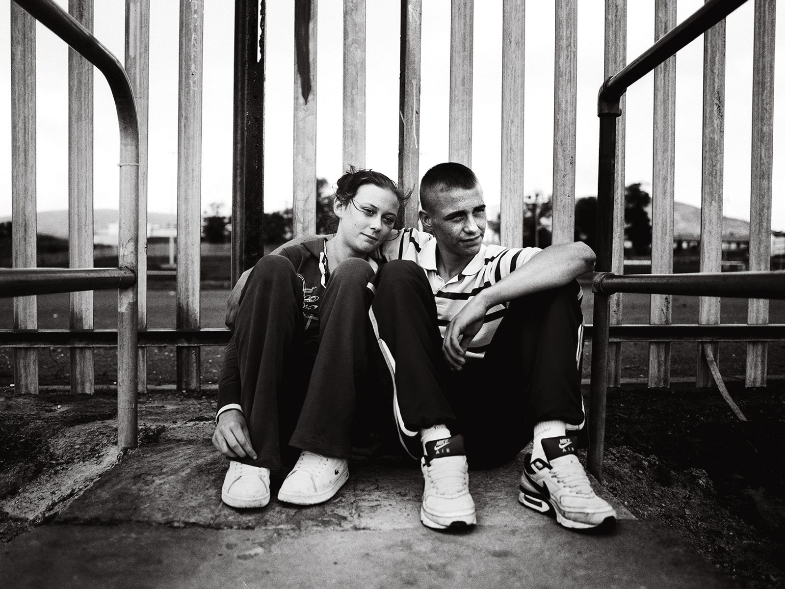 © Toby Binder - Belfast, Falls. Young couple sitting in front of a fence.