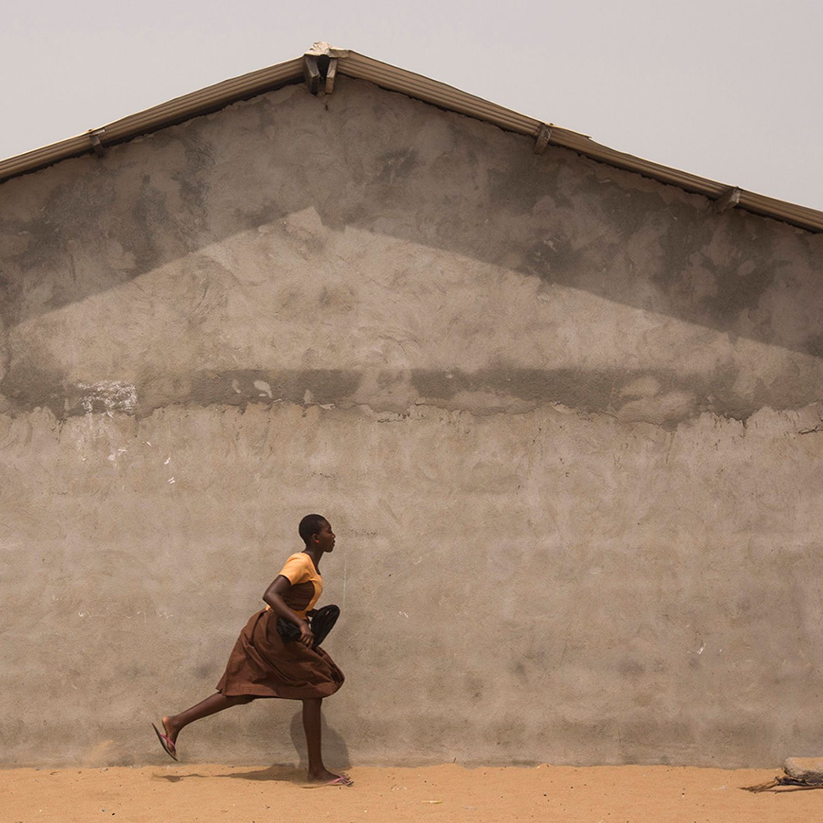 © Matilde Gattoni - Ghana - Fuveme - A schoolgirl runs for cover as the ocean waves start flooding the village.