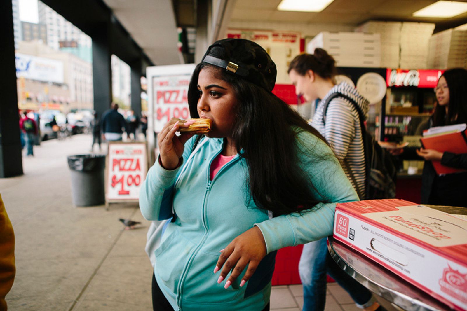 © Cassandra Giraldo - Anna Pimentel, 16, enjoys a slice of pizza after school on Flatbush Avenue in Brooklyn, New York October 27, 2015.