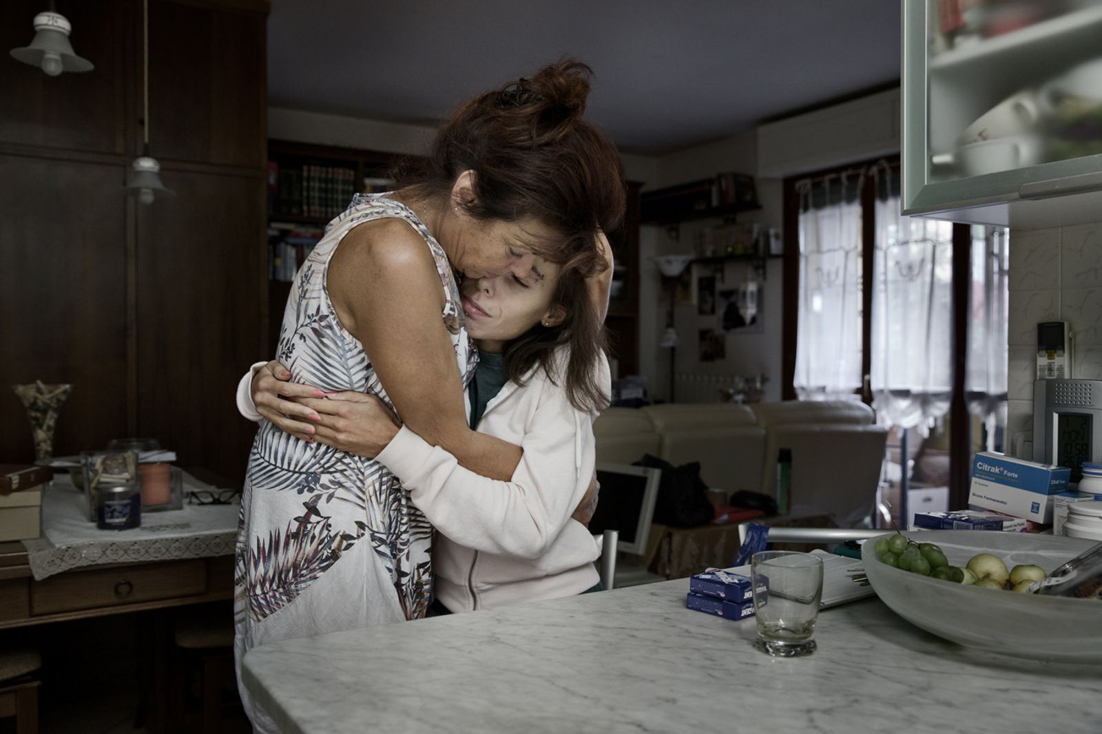 © Leonardo Chiarabini - Vanessa and her mother enbrace in their's kitchen. Florence, Italy.