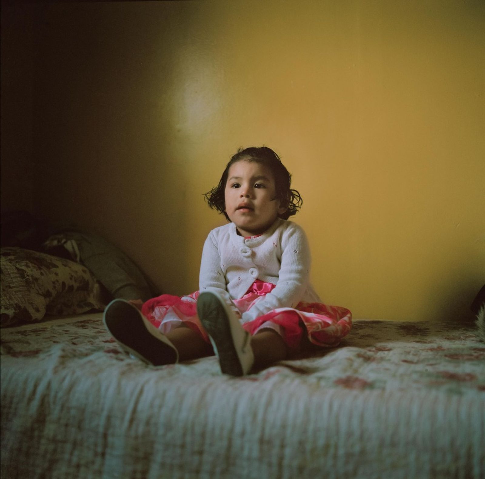 © Ruth Prieto - Lluvia sits on her bed with a pink dress bought for special occasions.