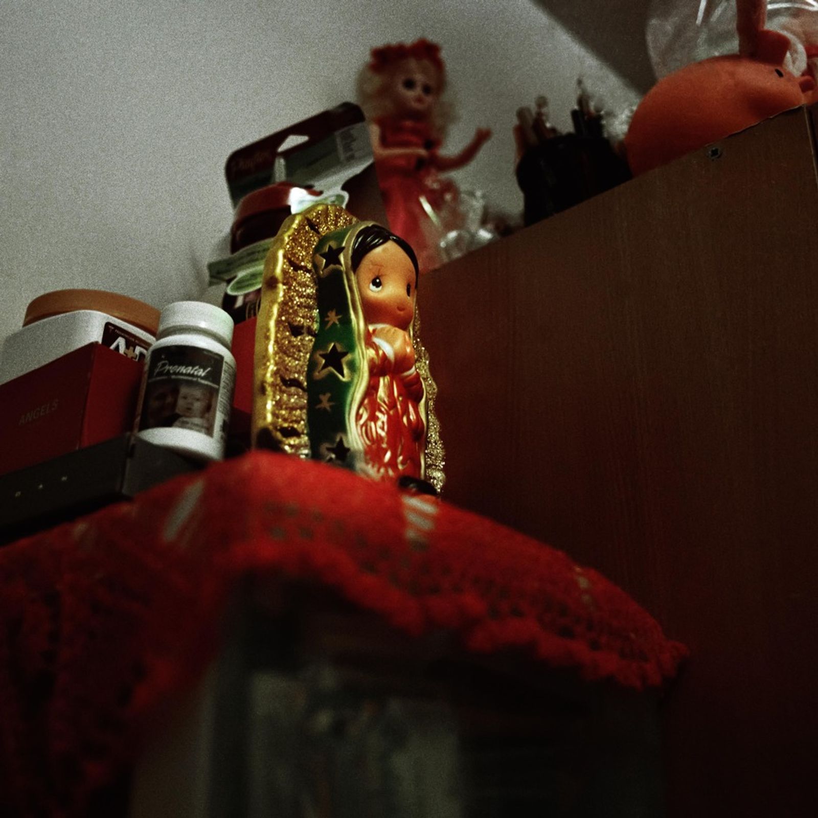 © Ruth Prieto - A Virgin of Guadalupe´s toy on the shelve. In the background a Barbie figure stands along with all the other toys.