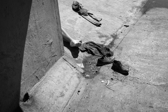 © Richard Sharum - A stripped man sits in the sun at the end of one of the tunnels, after getting high with an injection into his arm.